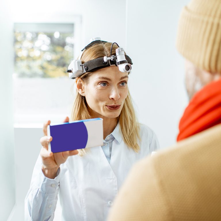 Doctor offering some anti-cold remedies for a sick man during a medical consultation in the clinic. Holding a box with blank space to copy paste